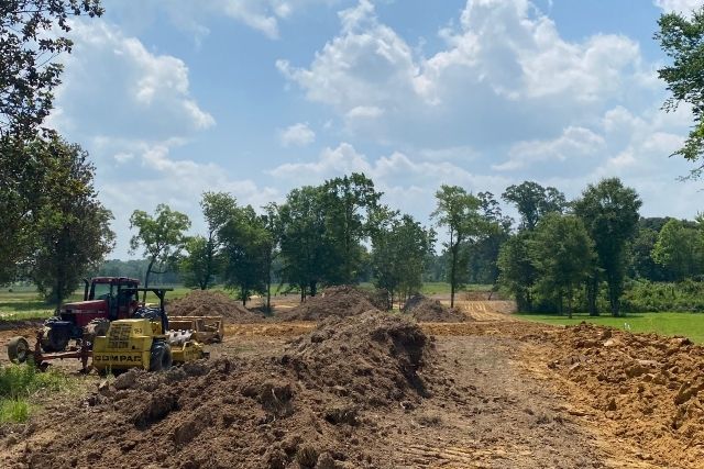 Site preparation with heavy dirt work to elevate land before home construction in a flood zone