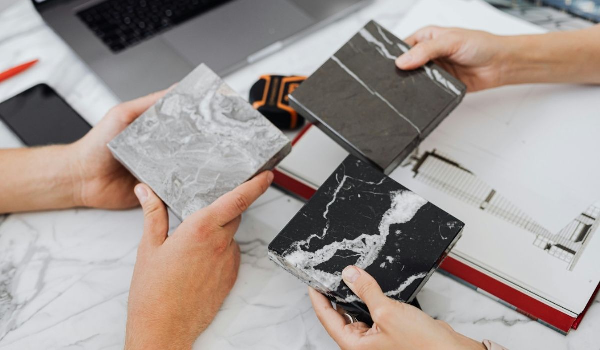 Hands holding quartz countertop samples during a custom home design meeting