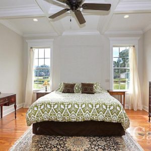 Master bedroom with heart pine floors, coffered ceiling, and windows with custom pediments flanking the bed