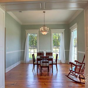 Paneled cased opening leading to dining room with chandelier