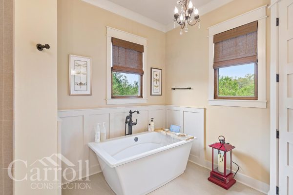 Master Bath with rectangular freestanding tub wainscoting feature chandelier and camel colored custom shades