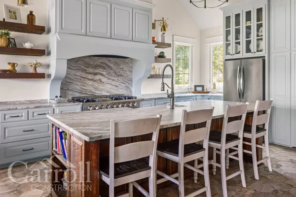 Kitchen with reclaimed wood island, grand vent hood, and stone backsplash behind THOR range