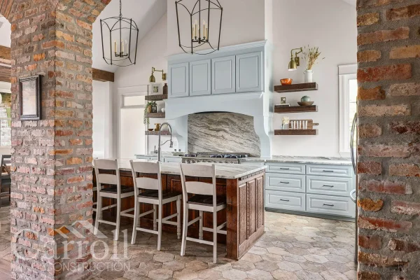 Outdoor kitchen range view framed by brick archway, featuring Blaze vent hood and cypress cabinets