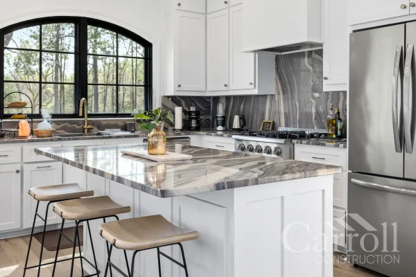 Kitchen with granite backsplash, matching island, Thor range, and arched window over the sink