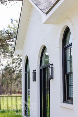 Side view of modern front door with slimline windows and wall-mounted outdoor sconce lights