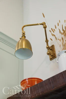 Articulating brass sconce over reclaimed pine floating shelves flanking the range hood