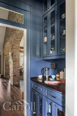 Blue wall butler’s pantry with reclaimed pine countertops and glass-front wine and liquor cabinets