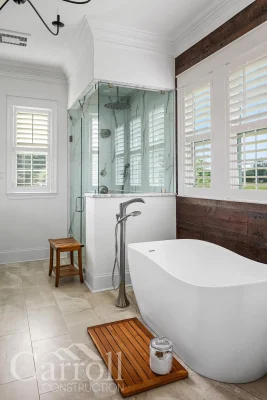 Insulated slipper tub in front of reclaimed pine feature wall with passive steam shower in background