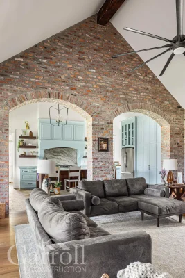 Double arch brick wall in living room with cathedral ceiling and central reclaimed pine beam