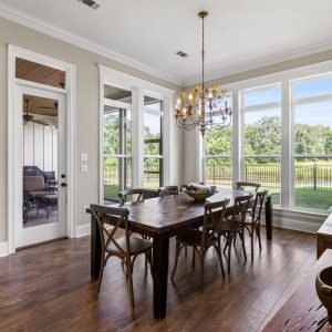 Dittmar Home – Liberty plan, 2,574 SF – dining room with beam entry, hardwood floors, wall of windows, and chandelier with historic provenance.