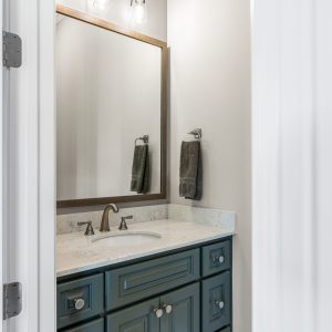 Dittmar Home – Liberty plan, 2,574 SF – half bath vanity with granite counters, dark cabinets, and wood-framed mirrors.