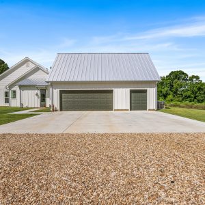 Dittmar Home – Liberty plan, 2,574 SF – exterior view facing garage with painted doors, Generac generators, and gravel approach.